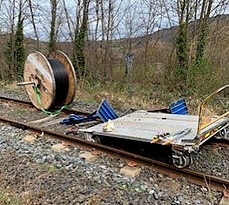 Un touret de câble tombé d'un lorry plateau, au sol à côté de la voie