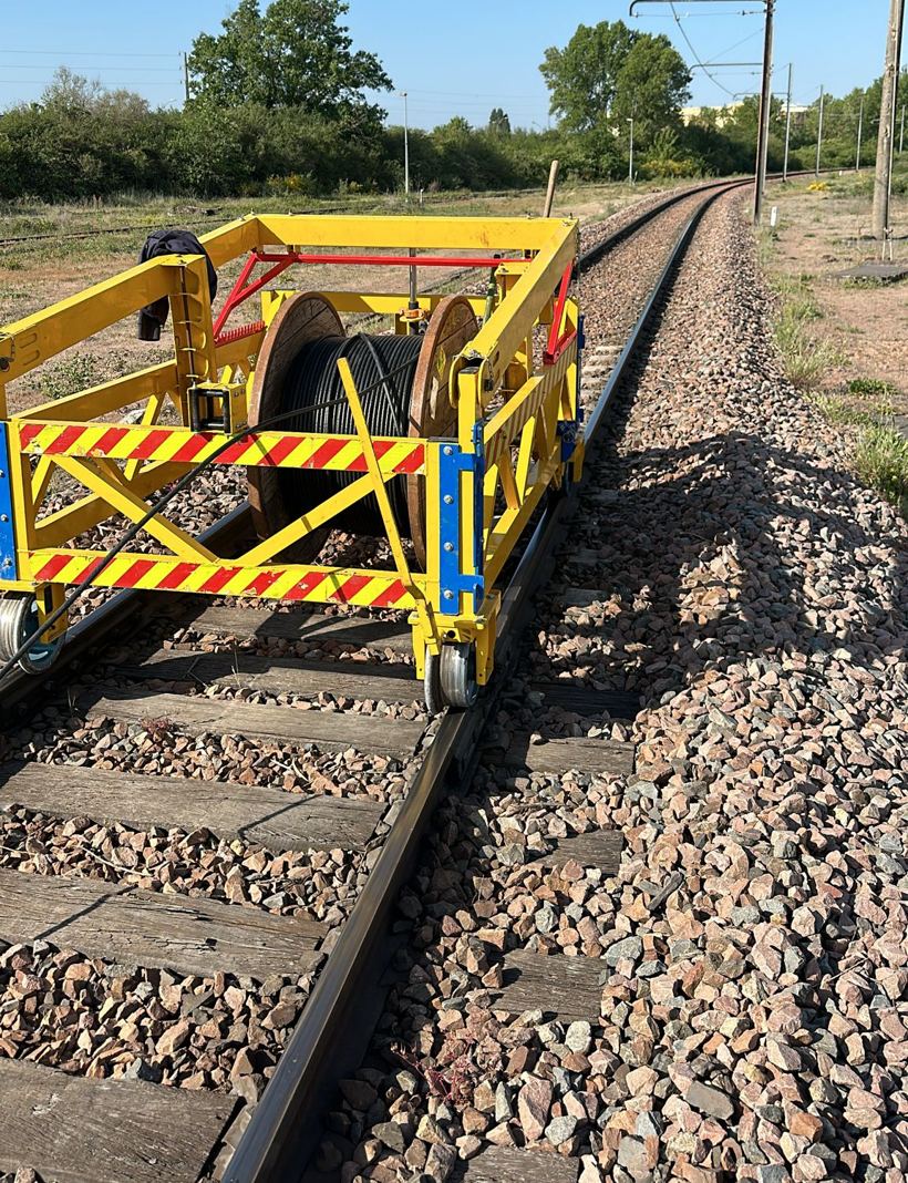 Le Lorry Dérouleur Mireille jaune, chargé d'un touret de câble, en voie sous caténaire